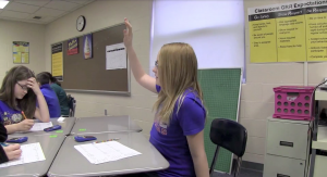 Middle school student in a classroom with handraised.
